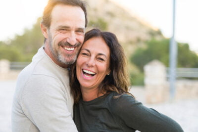 Romantic couple smiling and cuddling on a sunny day.